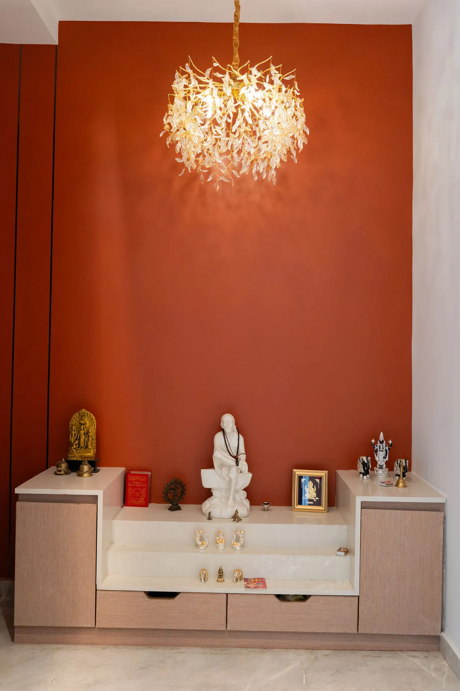 Pooja room with a marble mandir against a deep red wall