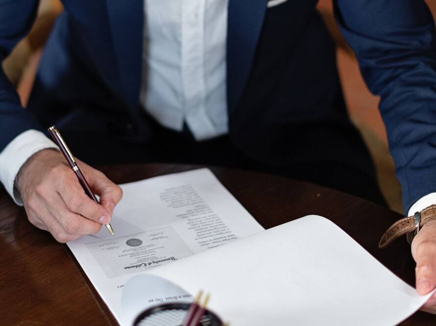 Signing a power of attorney document at a desk before sending it to India