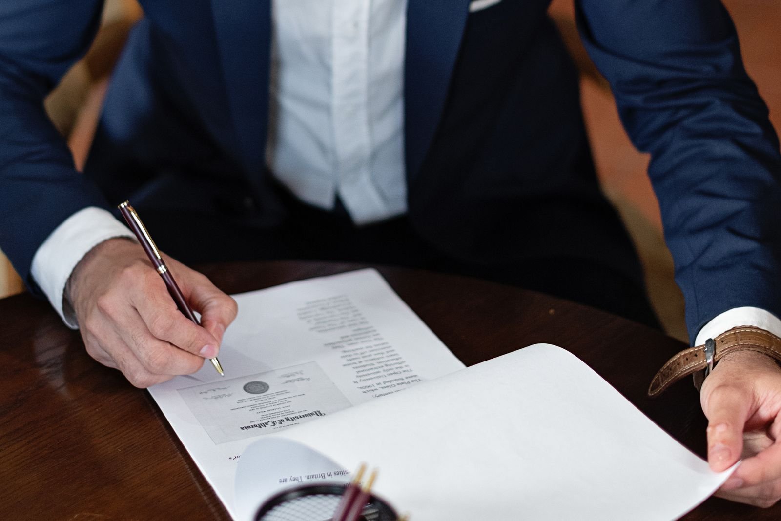 Signing a power of attorney document at a desk before sending it to India